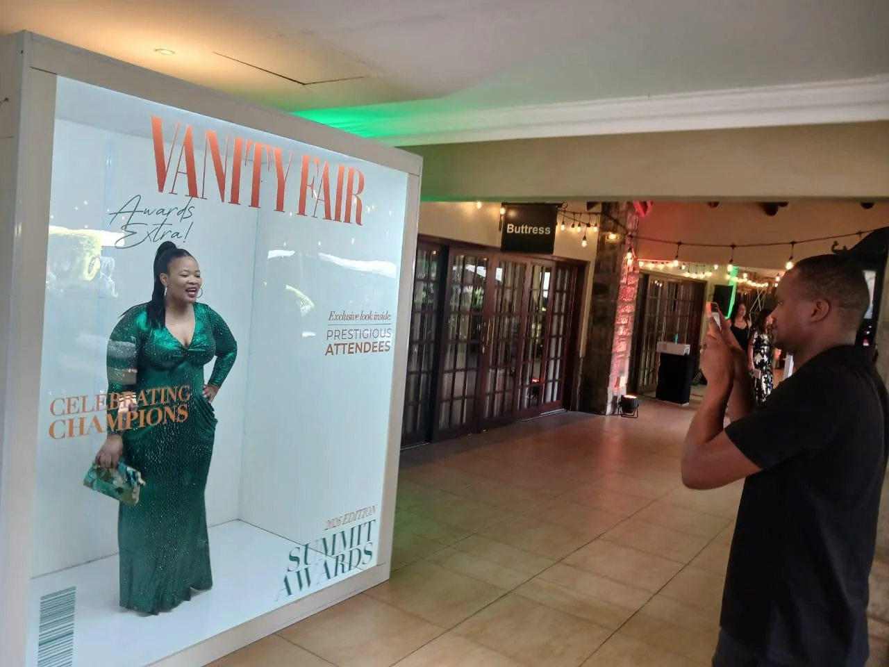 A woman in a green dress being photographed inside the awards magazine booth