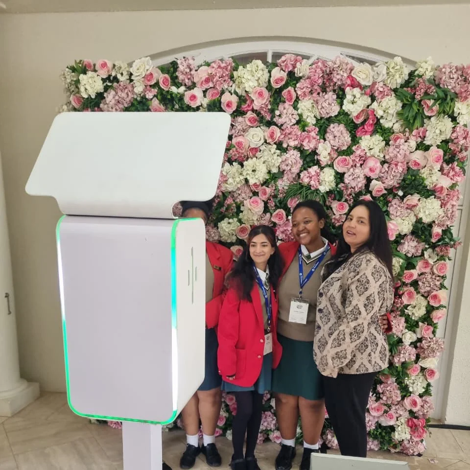 Guests posing with a SelfieBox booth in front of a pink floral wall