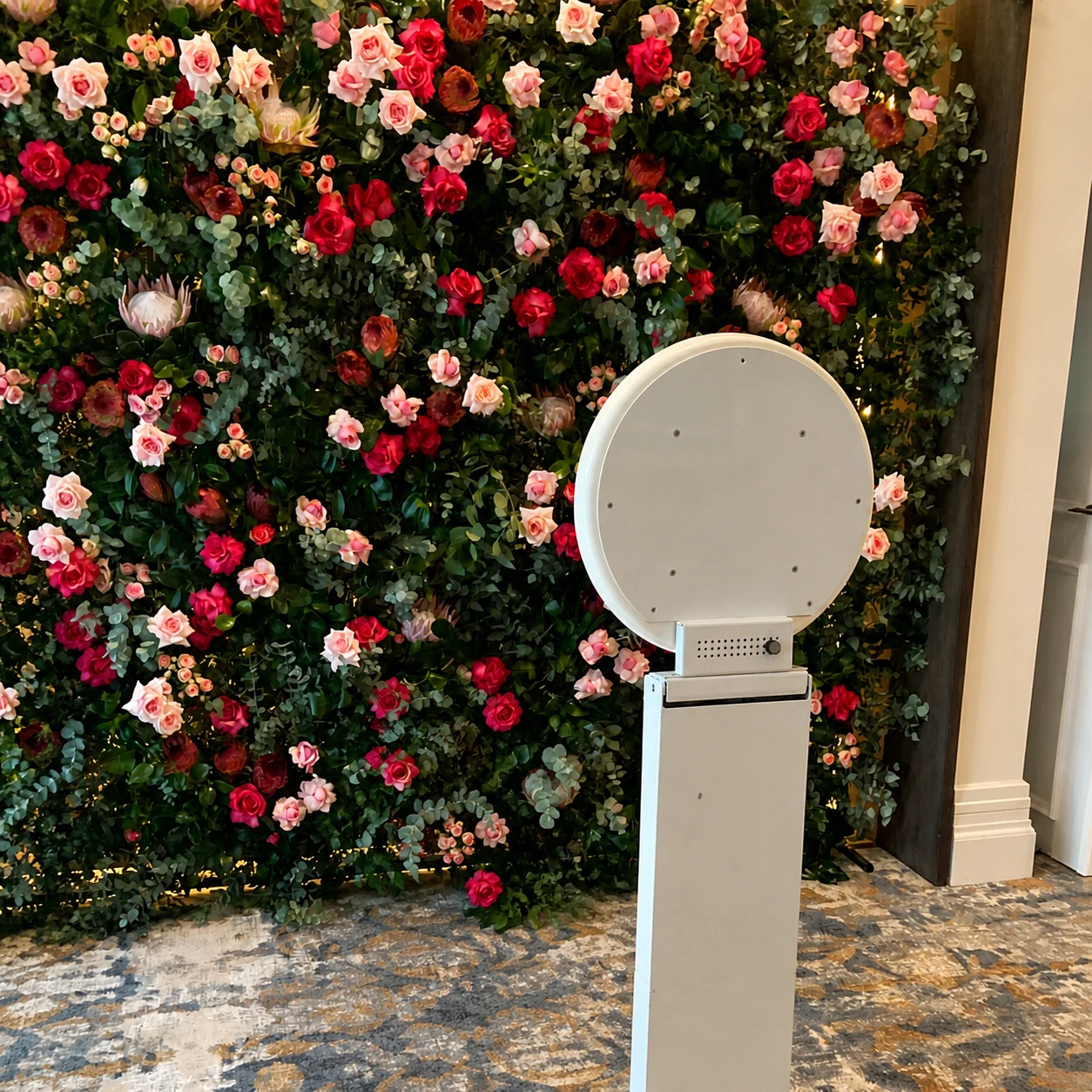 SelfieBox booth positioned in front of a colourful rose and greenery flower wall