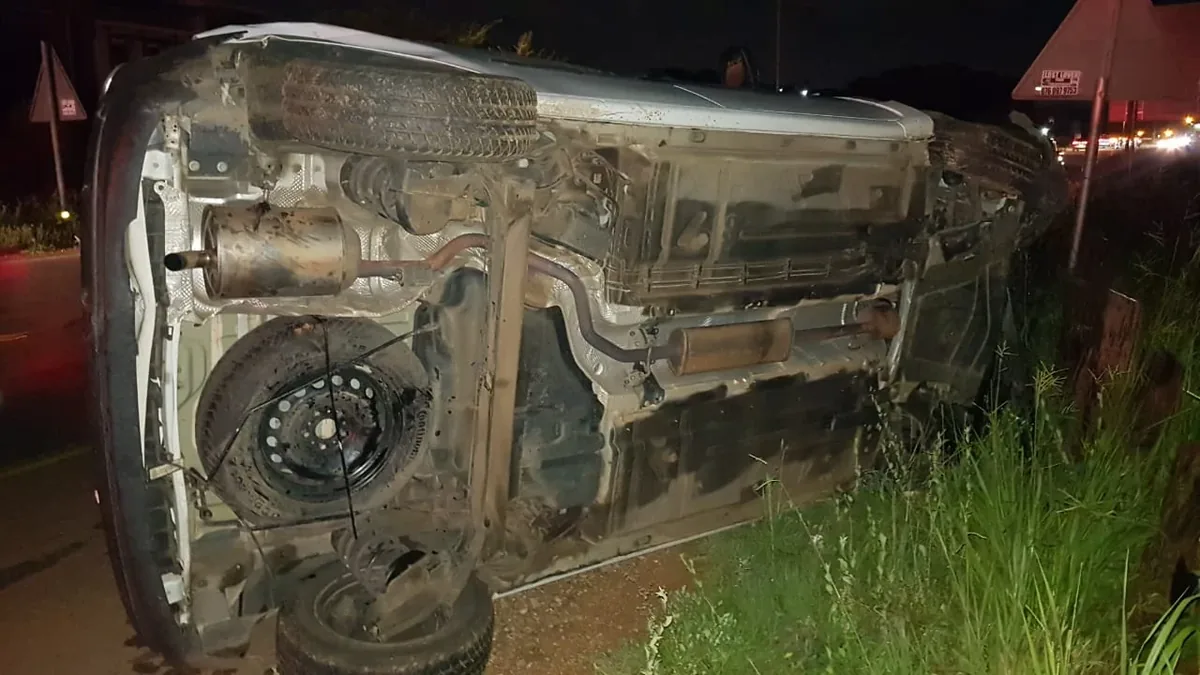 A vehicle on its side beside the road at night.