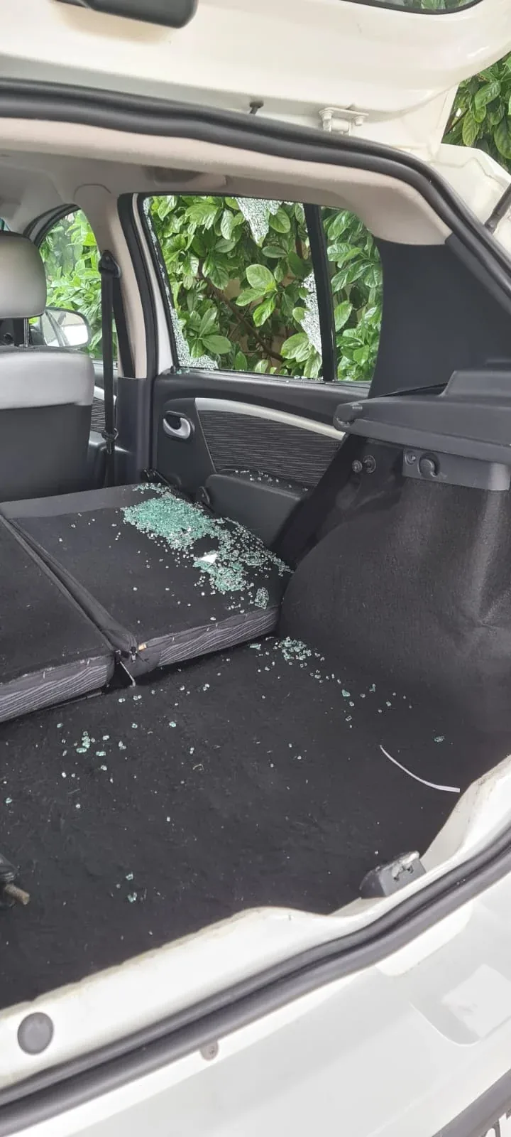 Broken vehicle glass scattered across the luggage area.