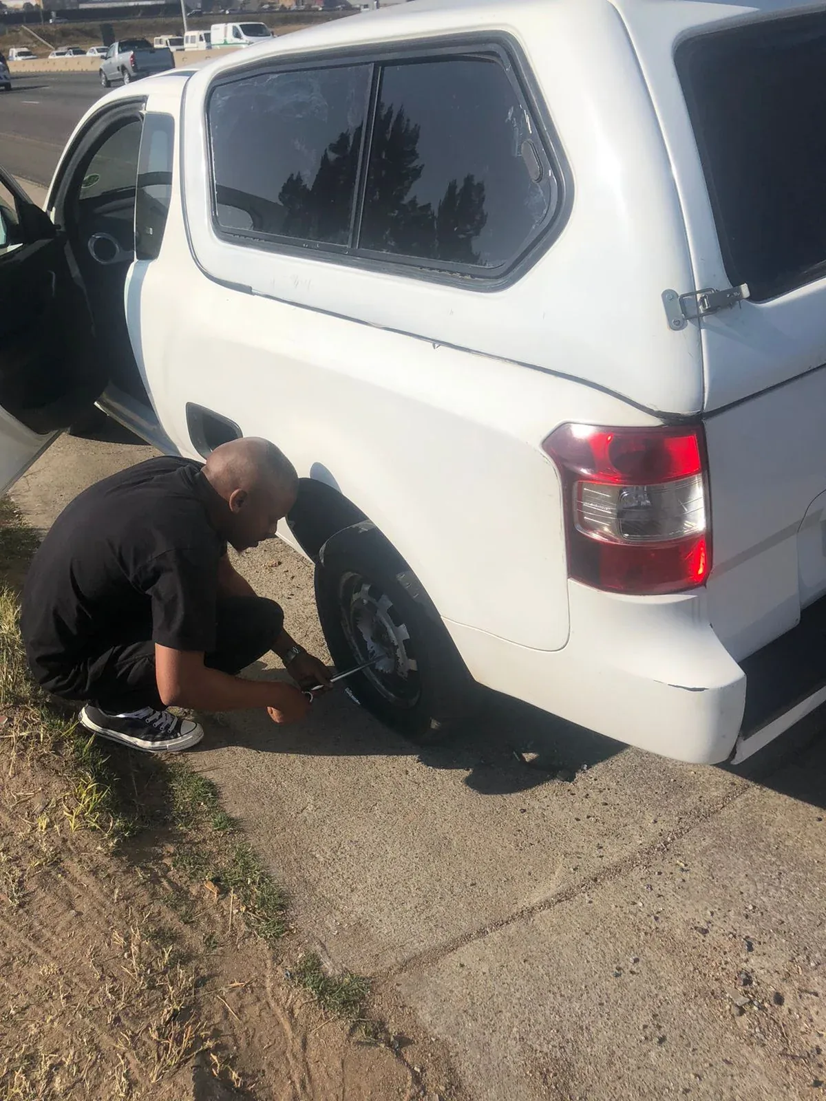 Changing a tyre beside a SelfieBox vehicle.