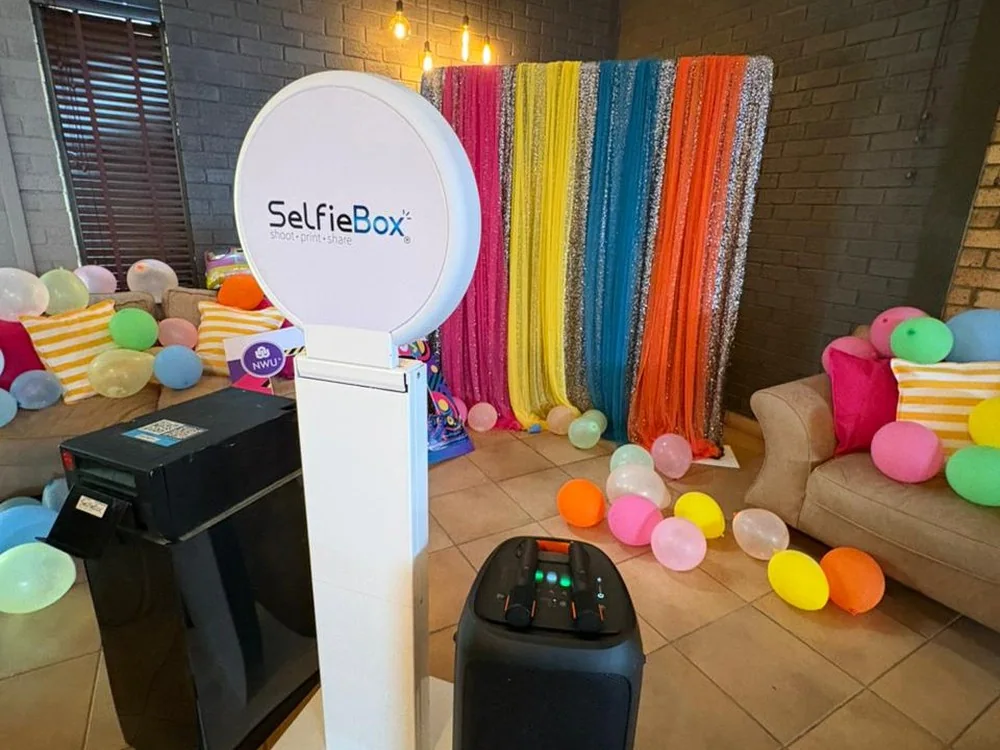 SelfieBox karaoke booth and sound equipment at a colourful event